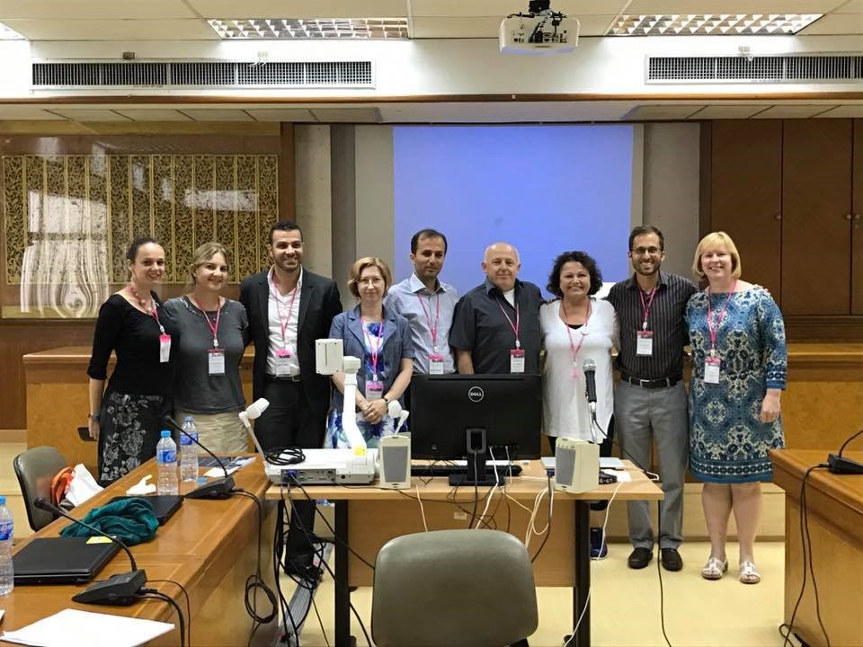 nine people stand in a conference room in front of the presentation screen for their conference panel. 