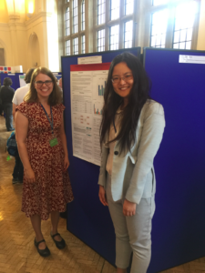 two women, Shelley Staples on left and Wendy Gao on right stand with their research poster at the 2017 Corpus Lingusitics conference. 